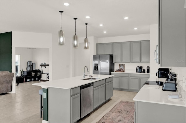 kitchen with a sink, gray cabinetry, an island with sink, and stainless steel appliances