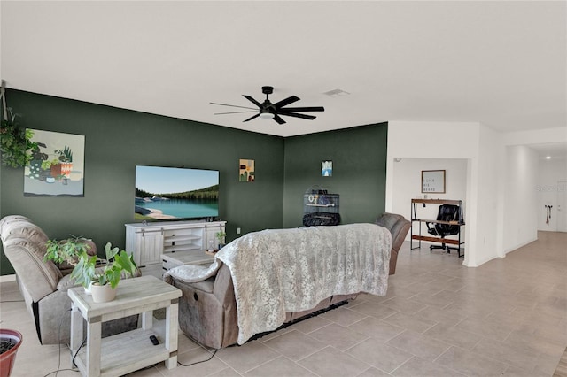 living room with an accent wall, visible vents, and ceiling fan