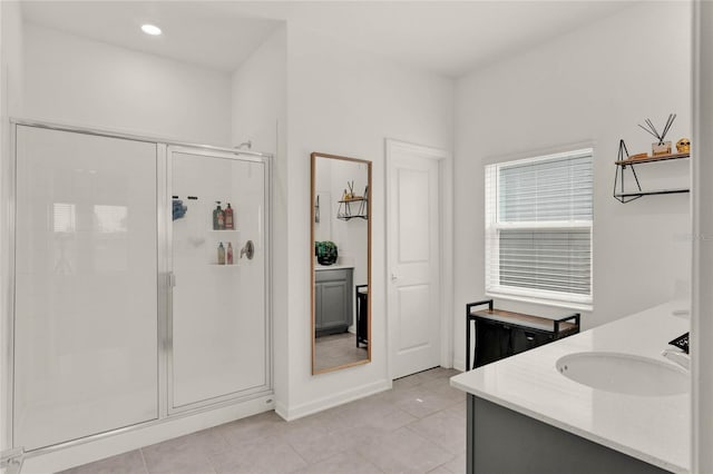 bathroom with tile patterned flooring, a stall shower, double vanity, and a sink