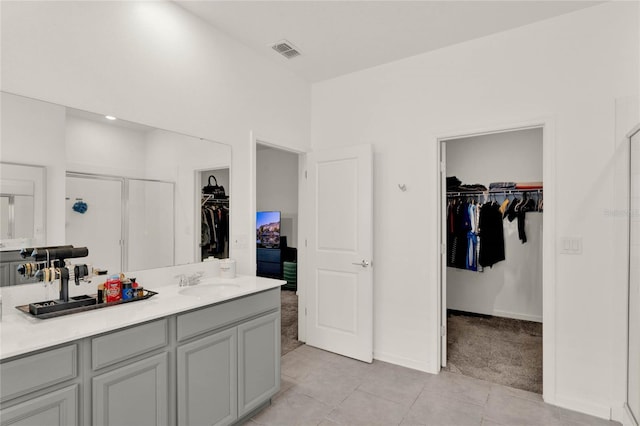 full bathroom featuring visible vents, a shower stall, a walk in closet, tile patterned floors, and vanity