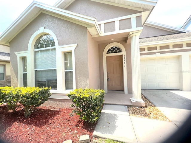 property entrance with stucco siding and an attached garage