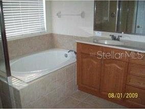 full bathroom featuring vanity, a shower with door, a bath, and tile patterned flooring