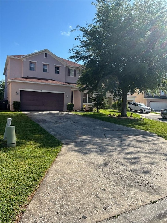 view of front facade with concrete driveway, stucco siding, a front yard, and a garage