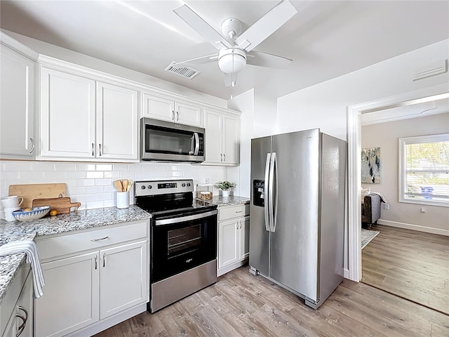 kitchen with light wood finished floors, backsplash, appliances with stainless steel finishes, and white cabinets