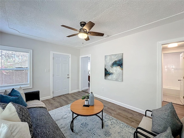 living room with baseboards, a textured ceiling, and wood finished floors