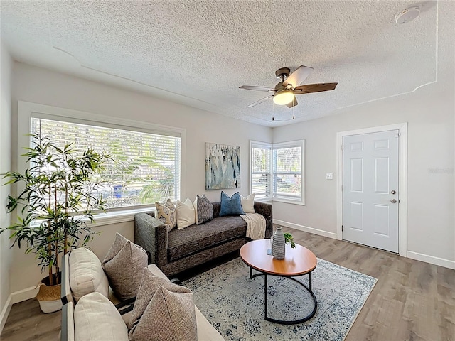 living area featuring a wealth of natural light, a textured ceiling, wood finished floors, and ceiling fan