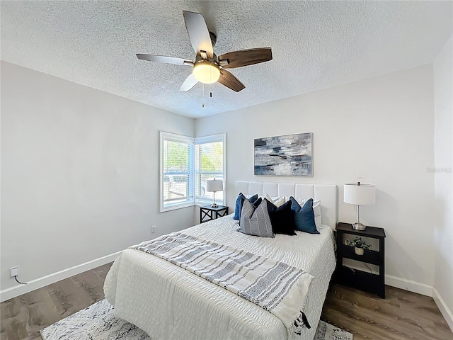 bedroom with ceiling fan, a textured ceiling, baseboards, and wood finished floors