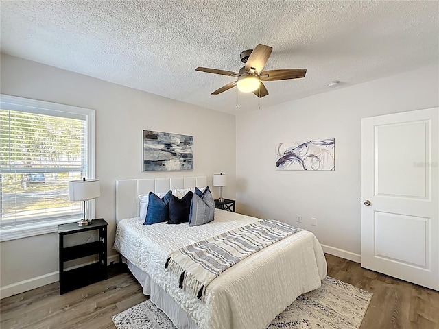 bedroom with a textured ceiling, baseboards, and wood finished floors