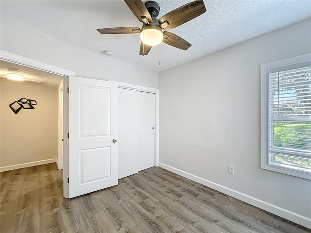 unfurnished bedroom with wood finished floors, baseboards, a closet, and a textured ceiling