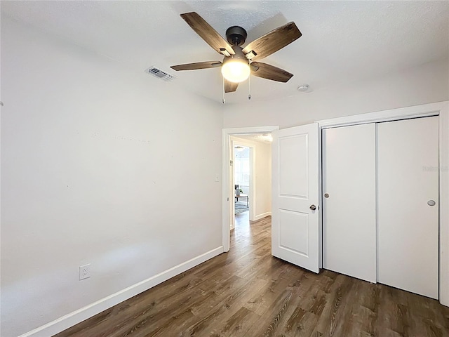 unfurnished bedroom featuring visible vents, ceiling fan, baseboards, wood finished floors, and a closet