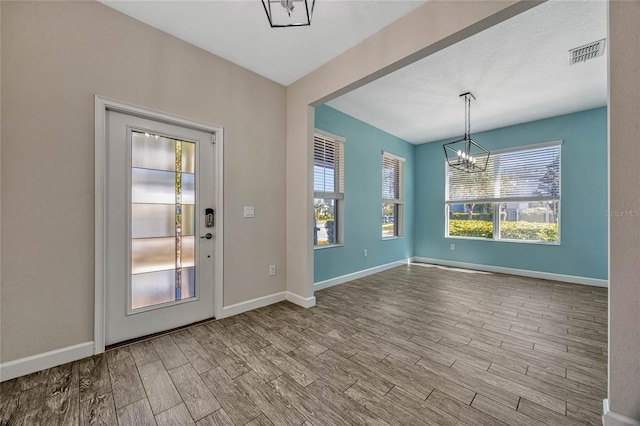 interior space with visible vents, baseboards, wood finished floors, and a chandelier