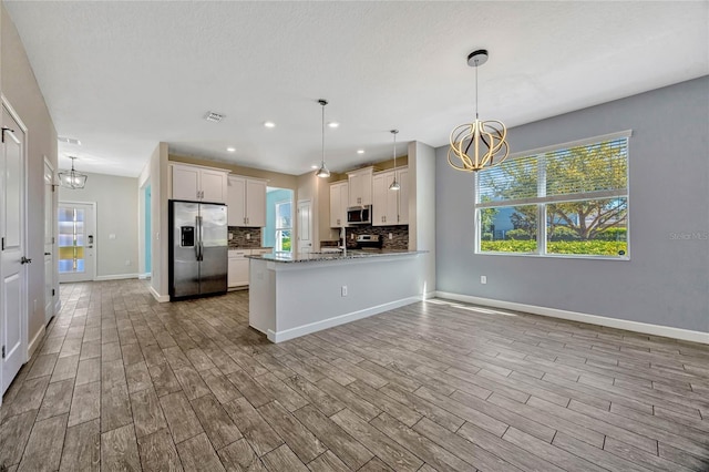 kitchen featuring tasteful backsplash, visible vents, appliances with stainless steel finishes, wood finished floors, and a notable chandelier