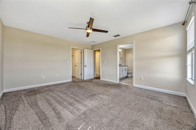 unfurnished bedroom with visible vents, ceiling fan, baseboards, carpet floors, and ensuite bath