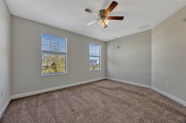 spare room featuring baseboards, visible vents, carpet floors, ceiling fan, and a textured ceiling