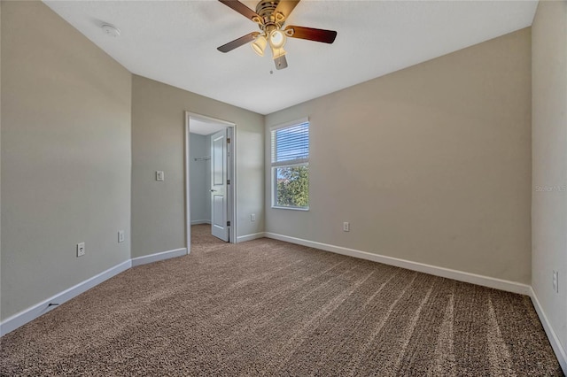 unfurnished bedroom with baseboards, carpet floors, a walk in closet, and a ceiling fan