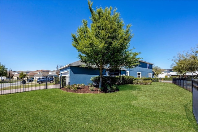 view of yard featuring a residential view, fence, a garage, and driveway