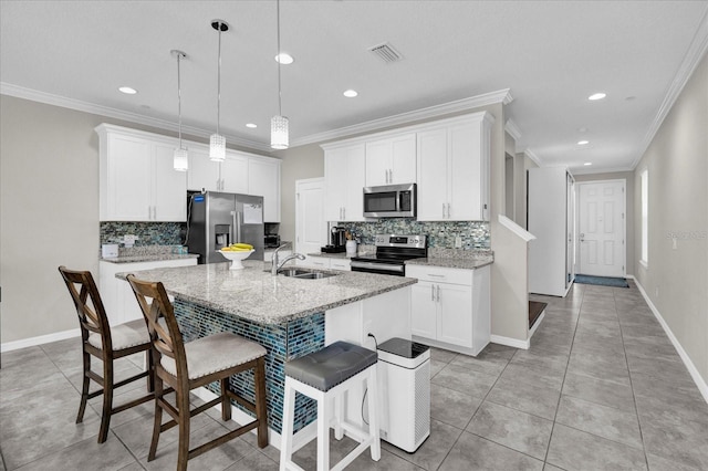 kitchen with visible vents, a center island with sink, a sink, a kitchen breakfast bar, and appliances with stainless steel finishes