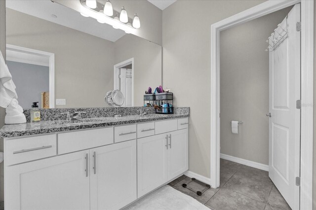 bathroom featuring double vanity, baseboards, tile patterned floors, and a sink