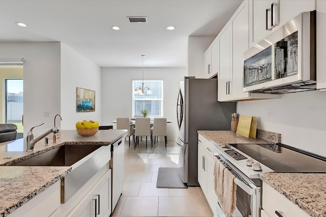 kitchen with dishwashing machine, light stone countertops, electric range, white cabinetry, and stainless steel microwave