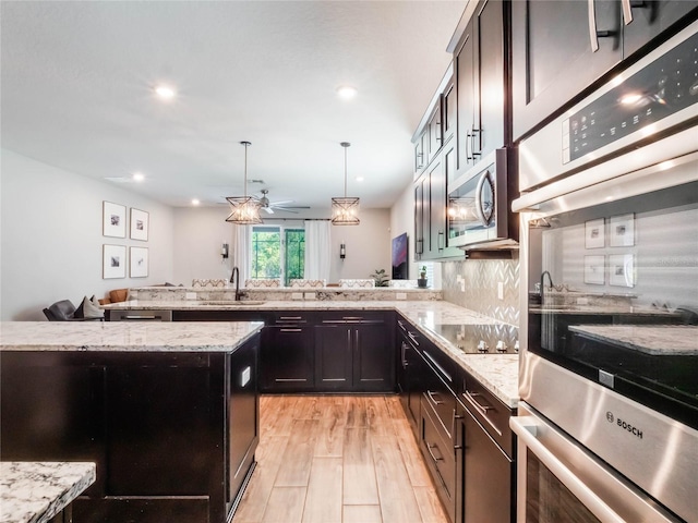 753 Daybreak Pl, Longwood, FL 32750 - kitchen featuring light stone countertops, a peninsula, a sink, appliances with stainless steel finishes, and pendant lighting