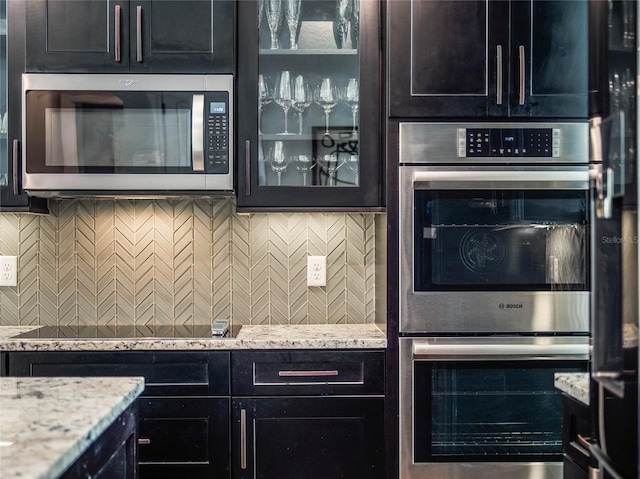 753 Daybreak Pl, Longwood, FL 32750 - kitchen with stainless steel appliances, light stone countertops, glass insert cabinets, and decorative backsplash
