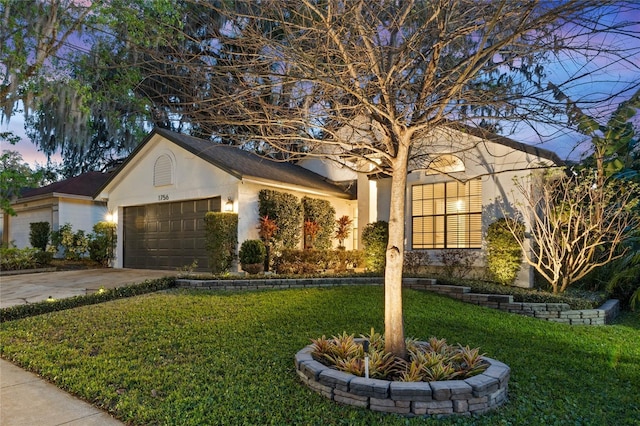 single story home with a lawn, concrete driveway, a garage, and stucco siding