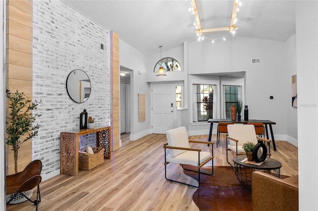 foyer entrance featuring visible vents, baseboards, high vaulted ceiling, and light wood-style flooring