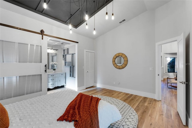 bedroom with wood finished floors, baseboards, visible vents, high vaulted ceiling, and track lighting