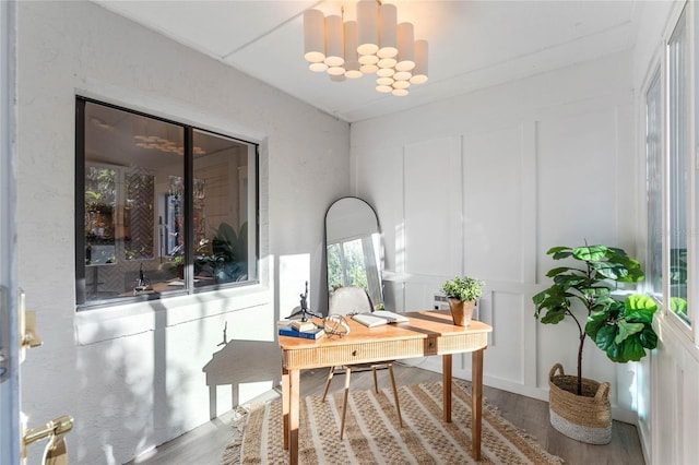 office space featuring a decorative wall, an inviting chandelier, and wood finished floors