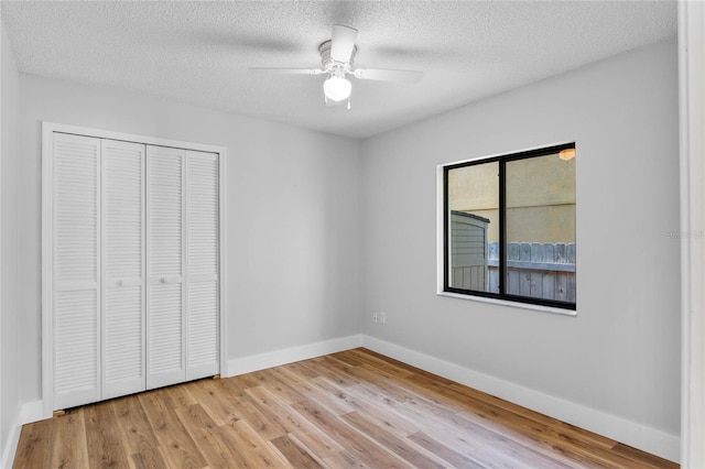 unfurnished bedroom with ceiling fan, baseboards, wood finished floors, a closet, and a textured ceiling