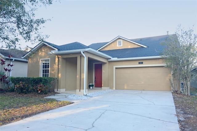 ranch-style home featuring stucco siding, an attached garage, and driveway