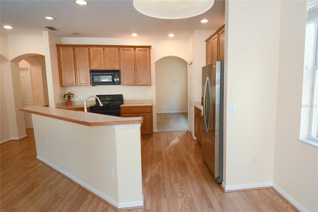 kitchen featuring black appliances, recessed lighting, arched walkways, light wood-style floors, and baseboards