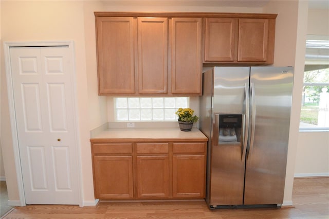 kitchen with light countertops, brown cabinetry, light wood-style floors, and stainless steel refrigerator with ice dispenser