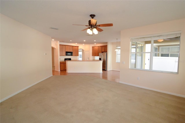 unfurnished living room featuring light carpet, visible vents, baseboards, and ceiling fan