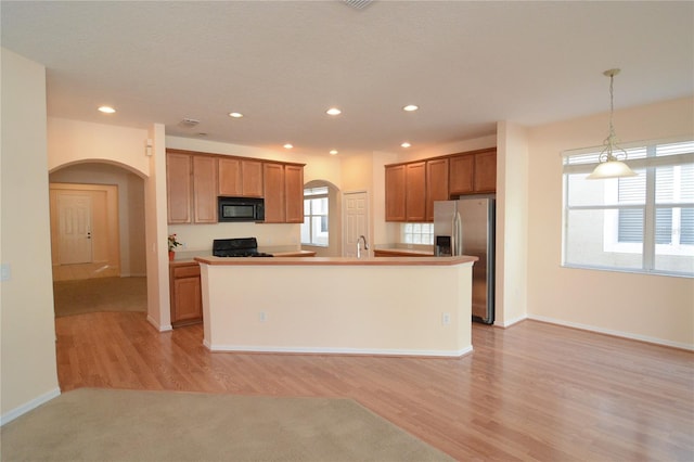 kitchen featuring plenty of natural light, stainless steel fridge with ice dispenser, arched walkways, black microwave, and range with gas cooktop