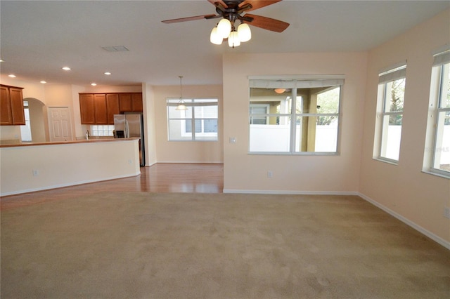 unfurnished living room featuring baseboards, carpet floors, recessed lighting, arched walkways, and a ceiling fan