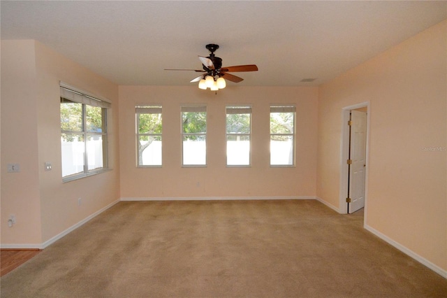 empty room with light colored carpet, baseboards, and a ceiling fan