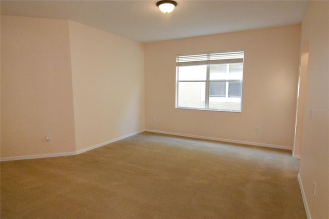 empty room featuring light colored carpet and baseboards