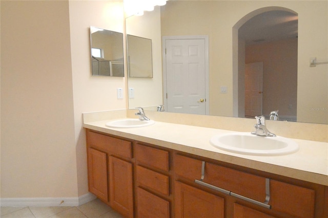 bathroom with a sink, baseboards, double vanity, and tile patterned flooring