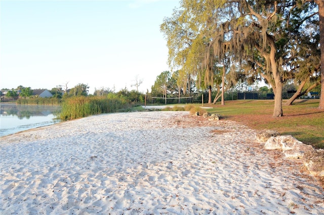 surrounding community featuring driveway, a lawn, a water view, and volleyball court