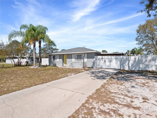 ranch-style house featuring driveway, a front lawn, and fence