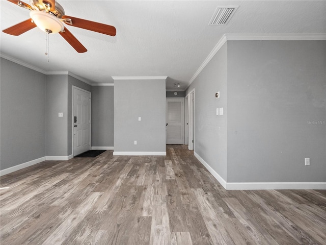 unfurnished living room with wood finished floors, baseboards, visible vents, ceiling fan, and crown molding