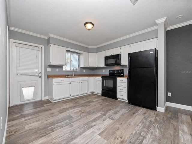 kitchen with light wood-type flooring, baseboards, black appliances, and white cabinetry