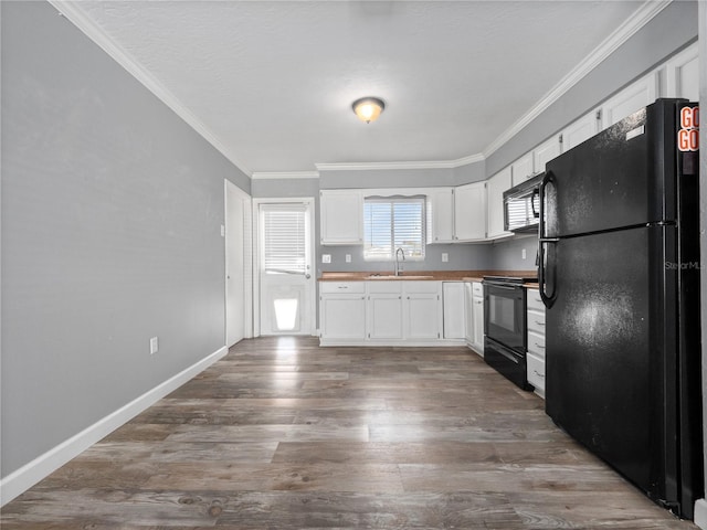 kitchen featuring black appliances, ornamental molding, wood finished floors, white cabinetry, and a sink