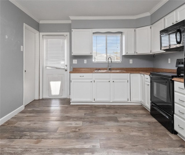 kitchen with a sink, black appliances, wood finished floors, and crown molding