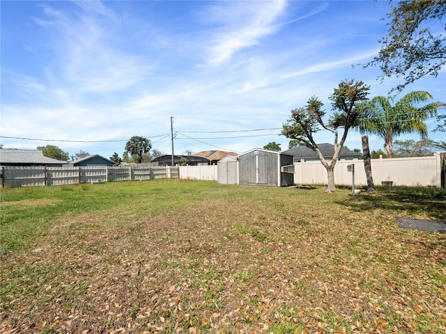 view of yard with a storage unit, an outdoor structure, and a fenced backyard