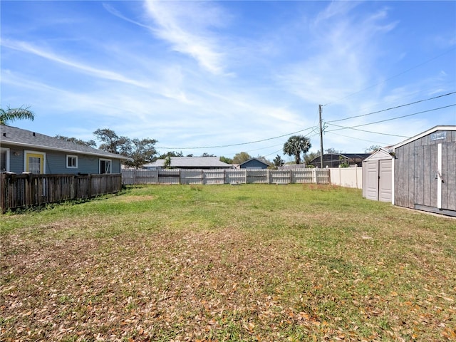 view of yard with a storage shed, a fenced backyard, and an outbuilding