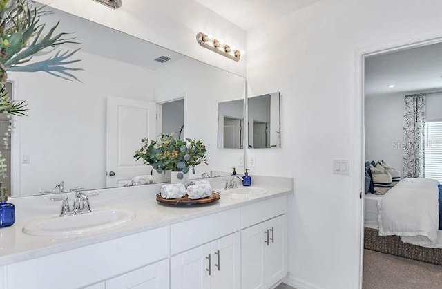 ensuite bathroom with double vanity, ensuite bath, baseboards, and a sink