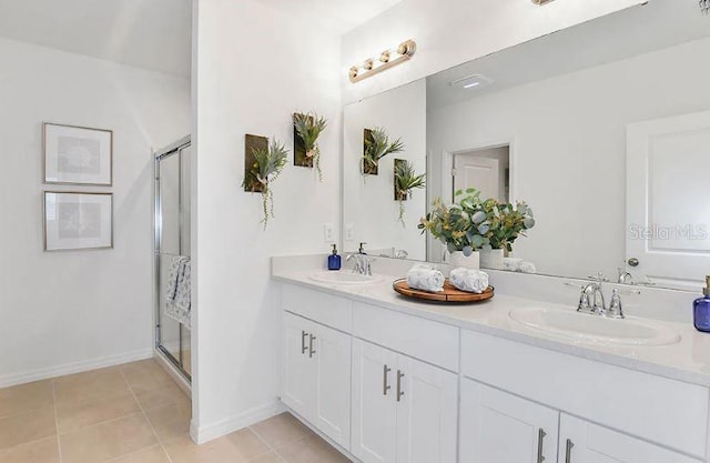 bathroom featuring a sink, double vanity, a shower stall, and tile patterned flooring