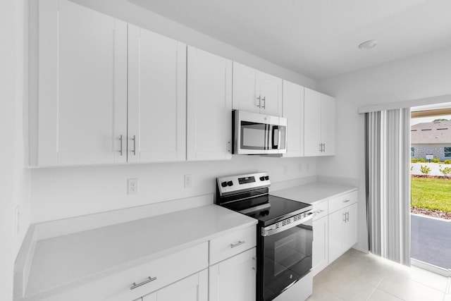 kitchen featuring light countertops, light tile patterned flooring, appliances with stainless steel finishes, and white cabinetry